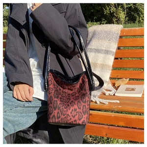 Close-up of leopard print bucket bag with black leather straps on a park bench