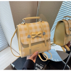 Detail of yellow checkered mini backpack with decorative bow and retro buckle closure