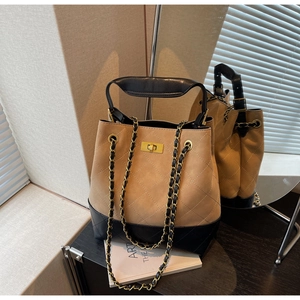 Detail view of quilted camel and black bucket bag with chain strap and gold lock