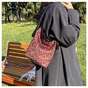 Detail of red leopard print bucket bag featuring premium leather strap and canvas texture