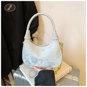 Sac hobo chic à motif marbre gris clair avec chaîne dorée tenu par un modèle