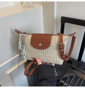 Detail der gewebten Stroh-Schultertasche mit braunem Lederbesatz und Metall-Quasten