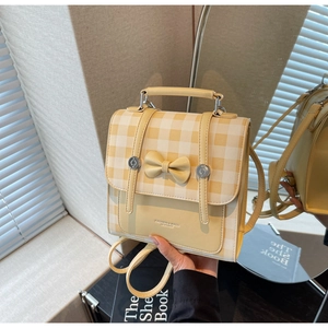 Detail of yellow plaid backpack with bow decor and dual buckled leather straps