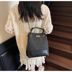 Detail of quilted leather bucket bag with gold chain strap and metal turn-lock closure