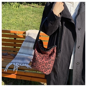 Detail of leopard print bucket bag with black patent leather straps in autumn outdoor setting