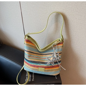 Detalle de un bolso tipo cubo de paja tejida a rayas con ribete de cuero y estrella
