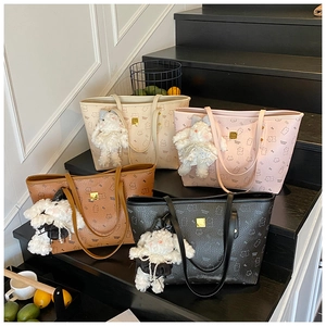 Detail view of four textured tote bags with bear print, luxury charms and gold hardware