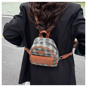 Close-up of a mini plaid backpack with leather trim worn over a black oversized blazer