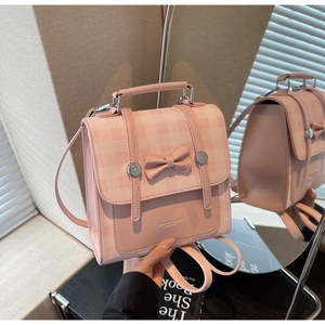 Close-up of pink plaid backpack with leather bow detail and silver buckles