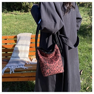 Outdoor shot of a stylish leopard print bucket bag with black leather shoulder strap