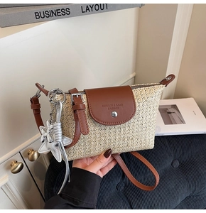 Detail der beigen Strohtasche mit brauner Lederklappe und silbernem Sternanhänger