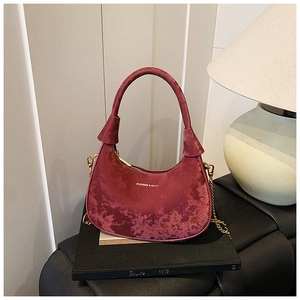 Détail du sac croissant en velours bordeaux avec chaîne et texte de mode