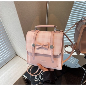 Pink checkered backpack detail showing bow accent and PU leather texture with strap