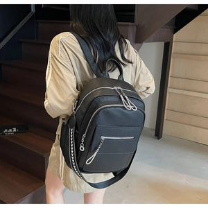 Close-up of black lychee texture leather backpack with multi-zipper and silver chain details