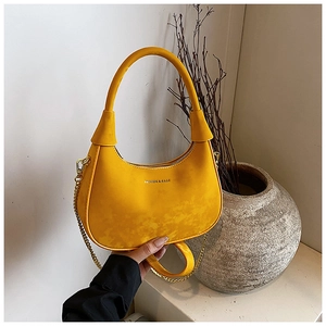 Gros plan du sac hobo croissant jaune vif avec chaîne dorée et texture daim mat