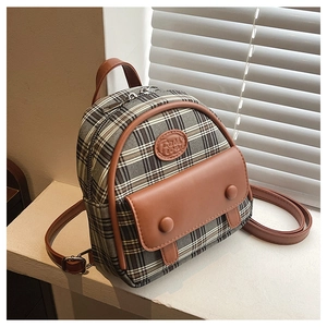 Nahaufnahme eines Vintage Karo-Minirucksacks in Grau mit braunen Lederdetails und Schnallen