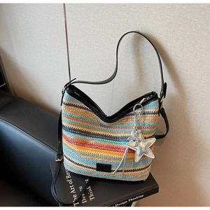 Detalle de bolso de paja tejido a rayas coloridas con correa de cuero y colgante estrella