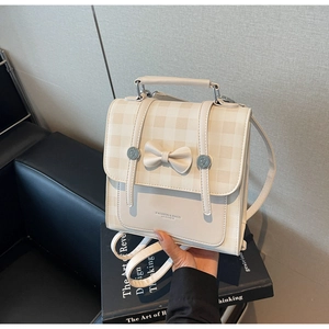 Detail of beige checkered backpack with decorative bow and metal buckle accents