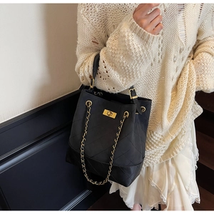 Close-up of quilted black leather texture and gold metal chain on the bucket bag