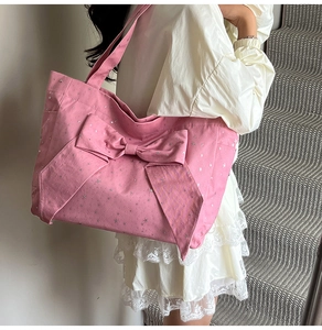 Close-up of pink canvas tote bag with silver star pattern and large decorative bow
