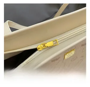 Close-up of beige faux leather tote with cat pattern embossing and gold metal zipper