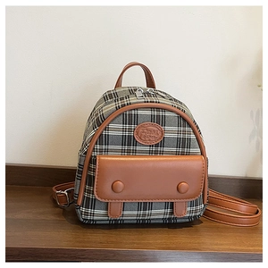Makro-Detail des Vintage-Karomusters und der braunen Lederpaspel am Mini-Rucksack