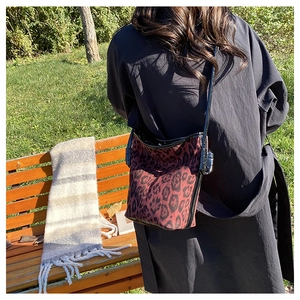 Detail of red-brown leopard print bucket bag on park bench with natural lighting