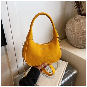 Détail du sac hobo jaune avec bandoulière chaîne dorée et texte embossé à la mode