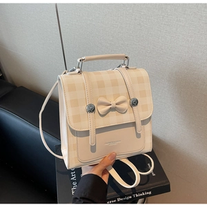 Detailed view of beige vintage backpack with plaid flap and decorative bow detail