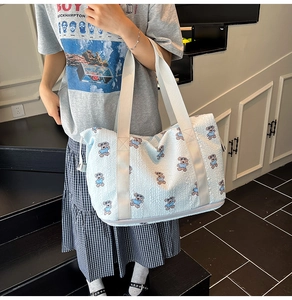 Detail of the light blue printed travel bag featuring bear patterns and sturdy woven handles