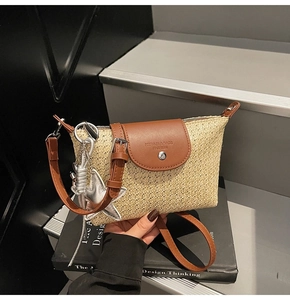 Detail der Strohtasche mit brauner Lederklappe, Magnetverschluss und silbernem Sternanhänger