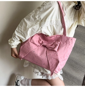Detail of pink canvas tote bag showing large bow, silver stars and textured fabric