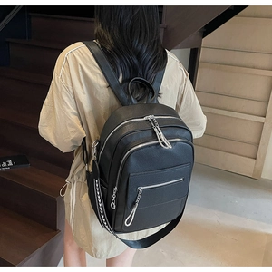 Detail of black pebbled leather backpack with silver zippers and woven decorative strap