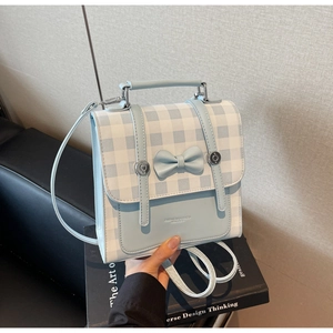 Detail view of light blue checkered backpack with decorative bow and vintage lettering
