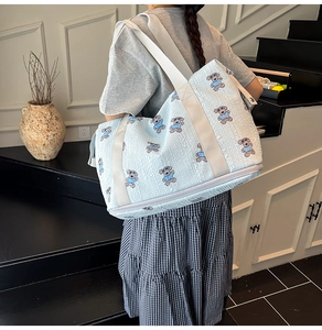 Detail of light blue cartoon bear travel bag showing the separate bottom zipper compartment