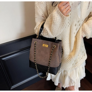 Close-up of diamond quilted pattern on vintage brown bucket bag with gold chain strap