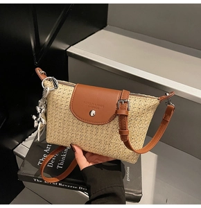Nahaufnahme der geflochtenen Strohtasche mit brauner Lederklappe und Silber-Anhänger