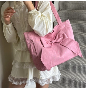 Detailed view of pink canvas tote bag featuring large bow and silver star patterns