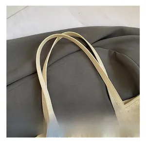 Detail of beige tote bag featuring pearl chain, plush charm and embossed cat pattern