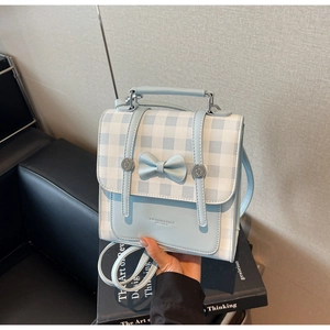 Detail view of the light blue leather and checkered canvas bag with a cute bow decoration