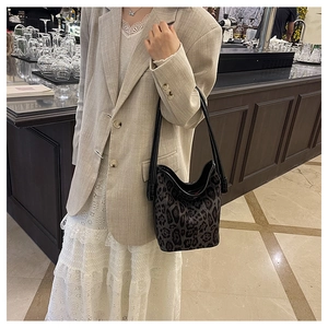Detailed view of leopard print bucket bag styled with a beige blazer and white lace skirt