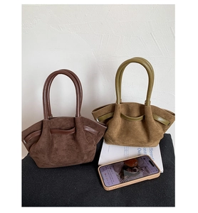 Detail view of suede tote bags in dark brown and olive green with drawstring design