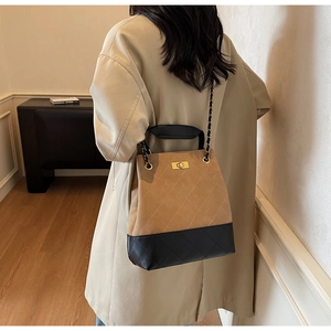 Detail view of quilted leather bucket bag with gold twist lock and chain strap on shoulder