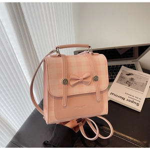 Pink checkered backpack with a decorative bow and elegant gold buckles on a table