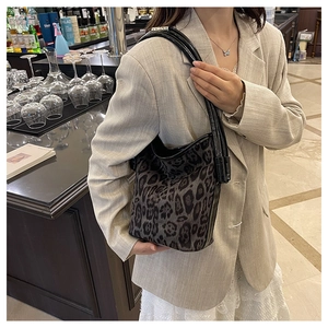 Detail of trendy leopard print bucket bag with black leather straps in a chic bar setting