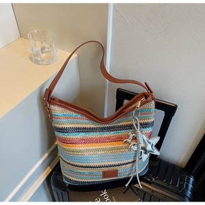 Detalle del bolso hobo tejido colorido con correa de cuero marrón y colgantes