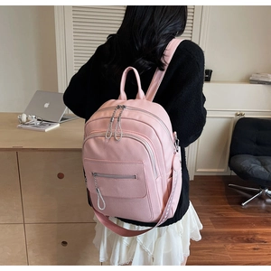 Rear view of a pink pebbled leather backpack showing size and fit on a person