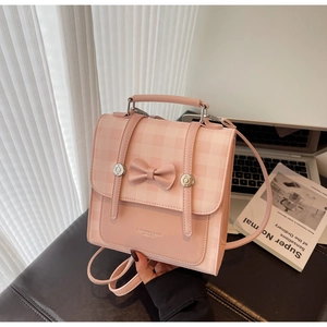 Pink checkered backpack with 3D bow detail shown in a stylish lifestyle setting