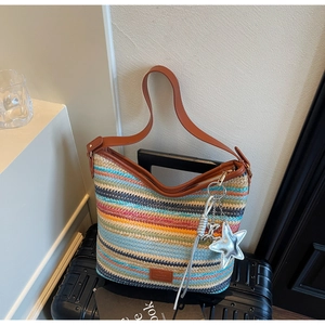 Detalle de bolso saco de paja tejida multicolor con correa de cuero y colgante estrella
