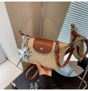 Detail der gewebten Strohtasche mit brauner Lederklappe und silbernen Anhängern